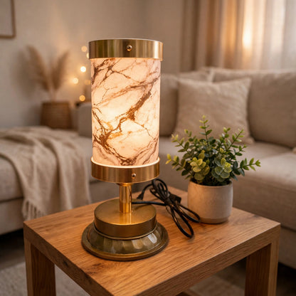 A table lamp with a glowing marble-patterned shade and a polished brass base sits on a wooden side table in a cozy living room setting.