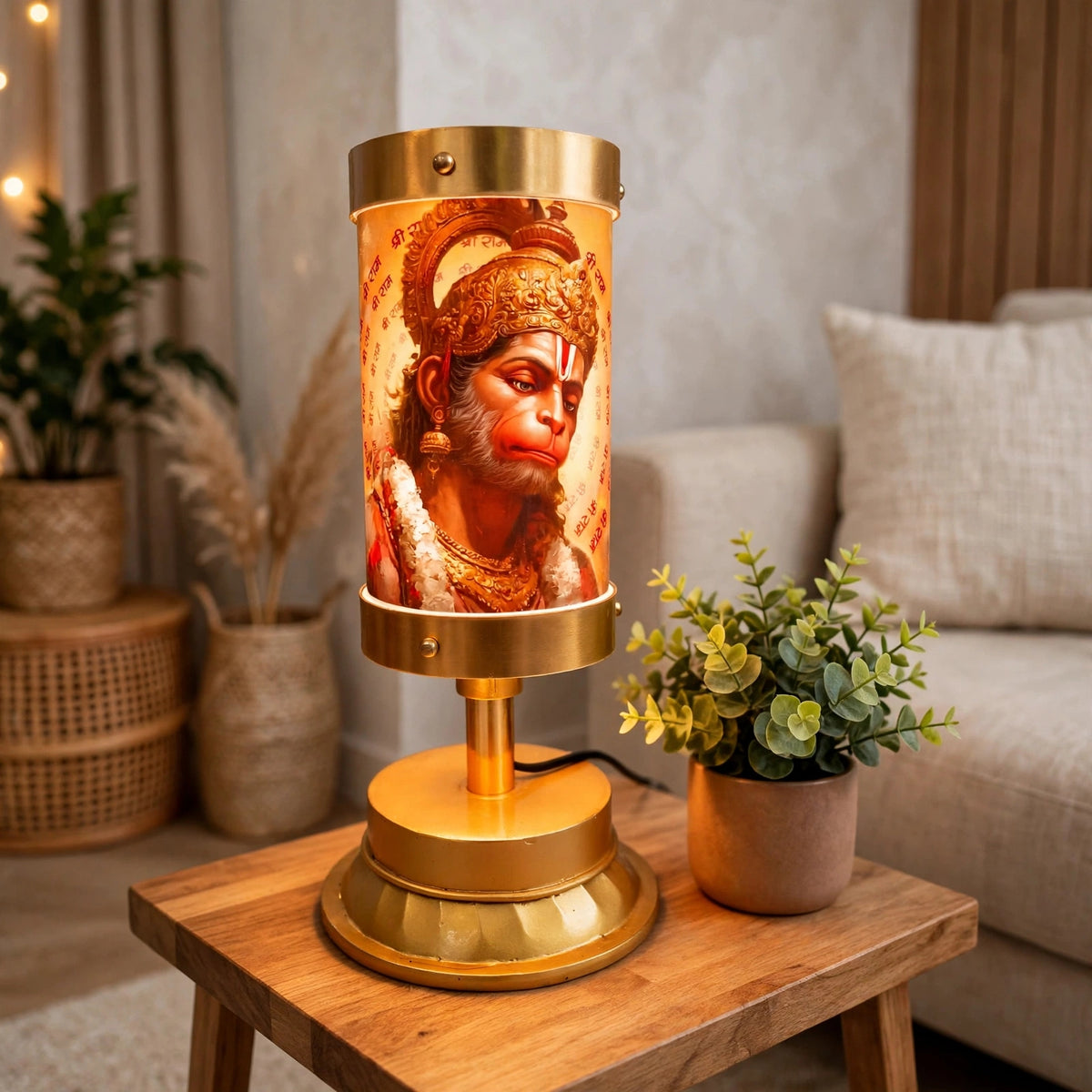 A brass table lamp featuring a detailed illuminated depiction of Lord Hanuman, styled on a wooden side table in a cozy living room setting.
