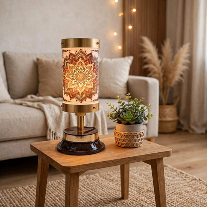 A decorative table lamp with a glowing mandala pattern on its cylindrical shade, set on a wooden side table in a cozy living room next to a small potted succulent.
